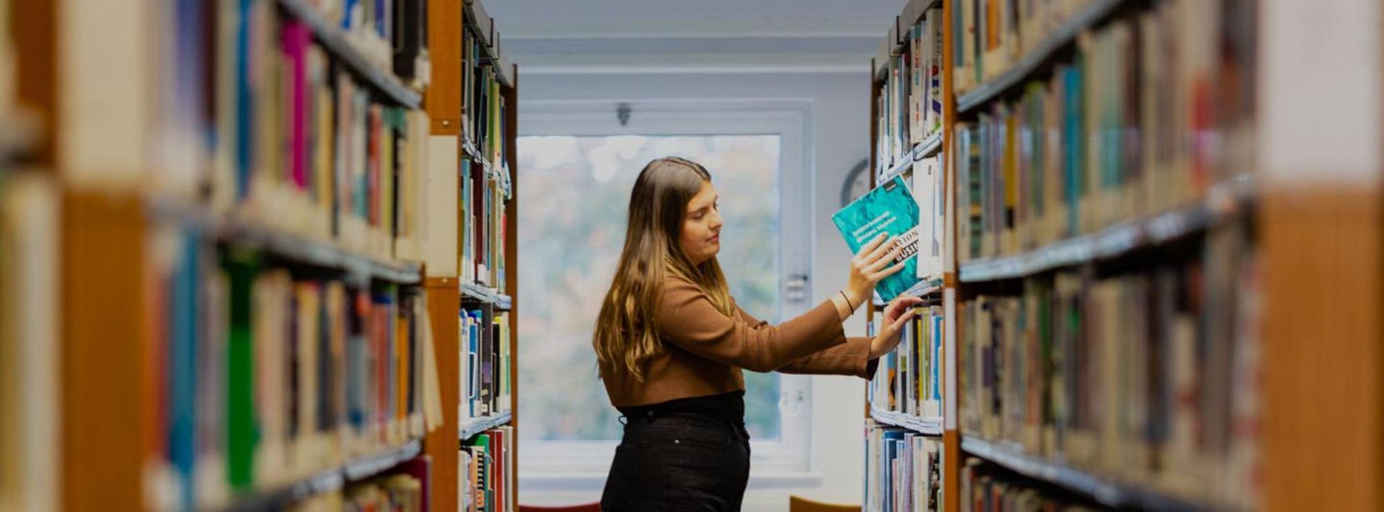 Student picking books off a shelf