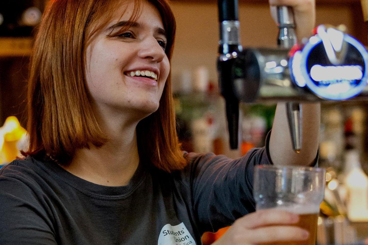 A female member of bar staff pours a drink