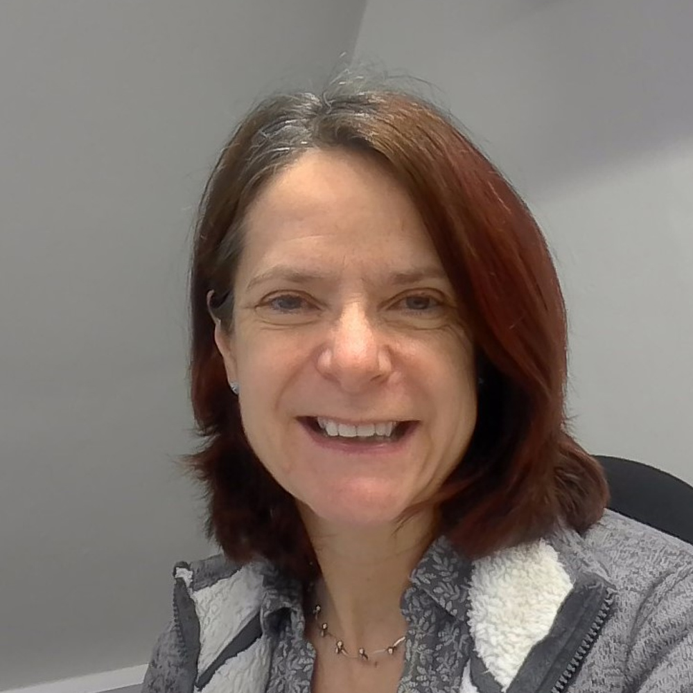 Person with shoulder-length auburn hair smiling